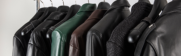 a row of different coloured and textured jackets hanging from hangers on a rack