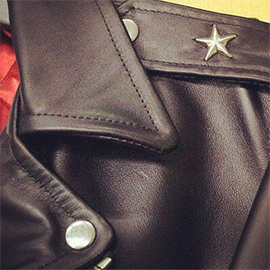 a close up of a leather jacket with a metal star sewn into the shoulder