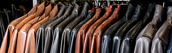 a row of different coloured leather jackets hanging on a rack 